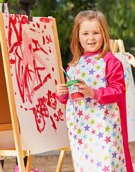 Girl wearing Pink Stars art smock painting at easel