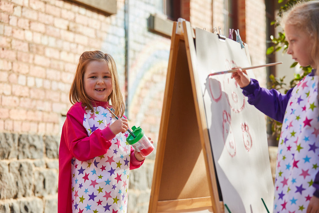 girls wearing stars art smocks and painting
